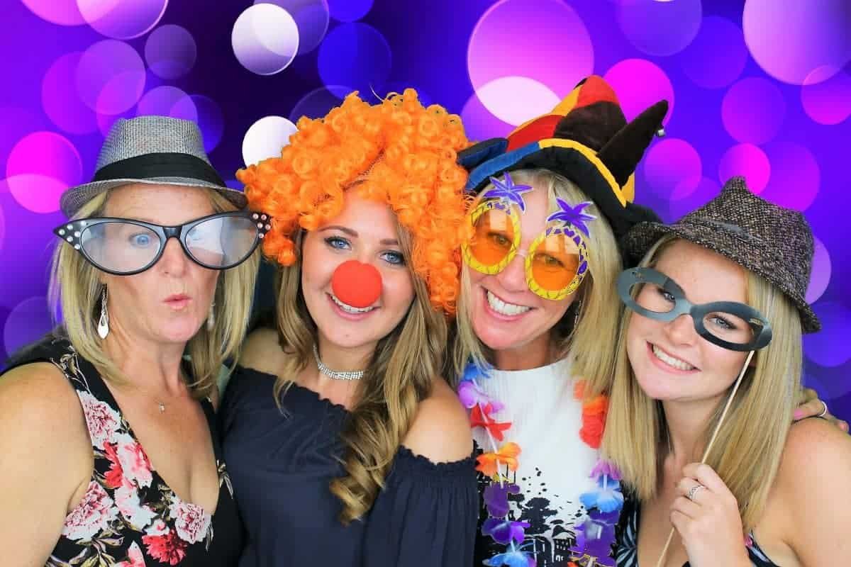 Group of women enjoying photo booth with fun props and colourful background