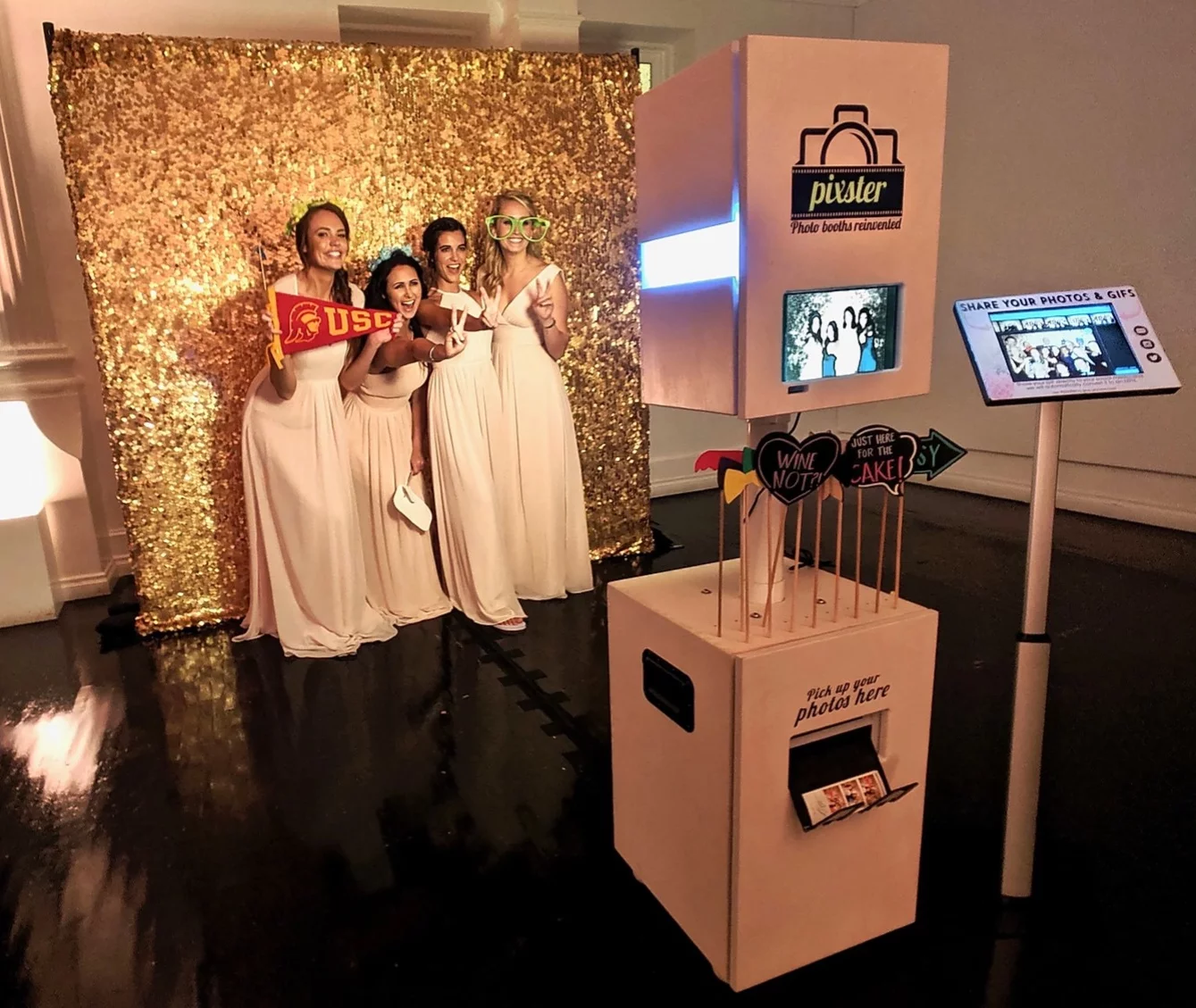 Bridesmaids using a modern open-air photo booth with gold backdrop at wedding