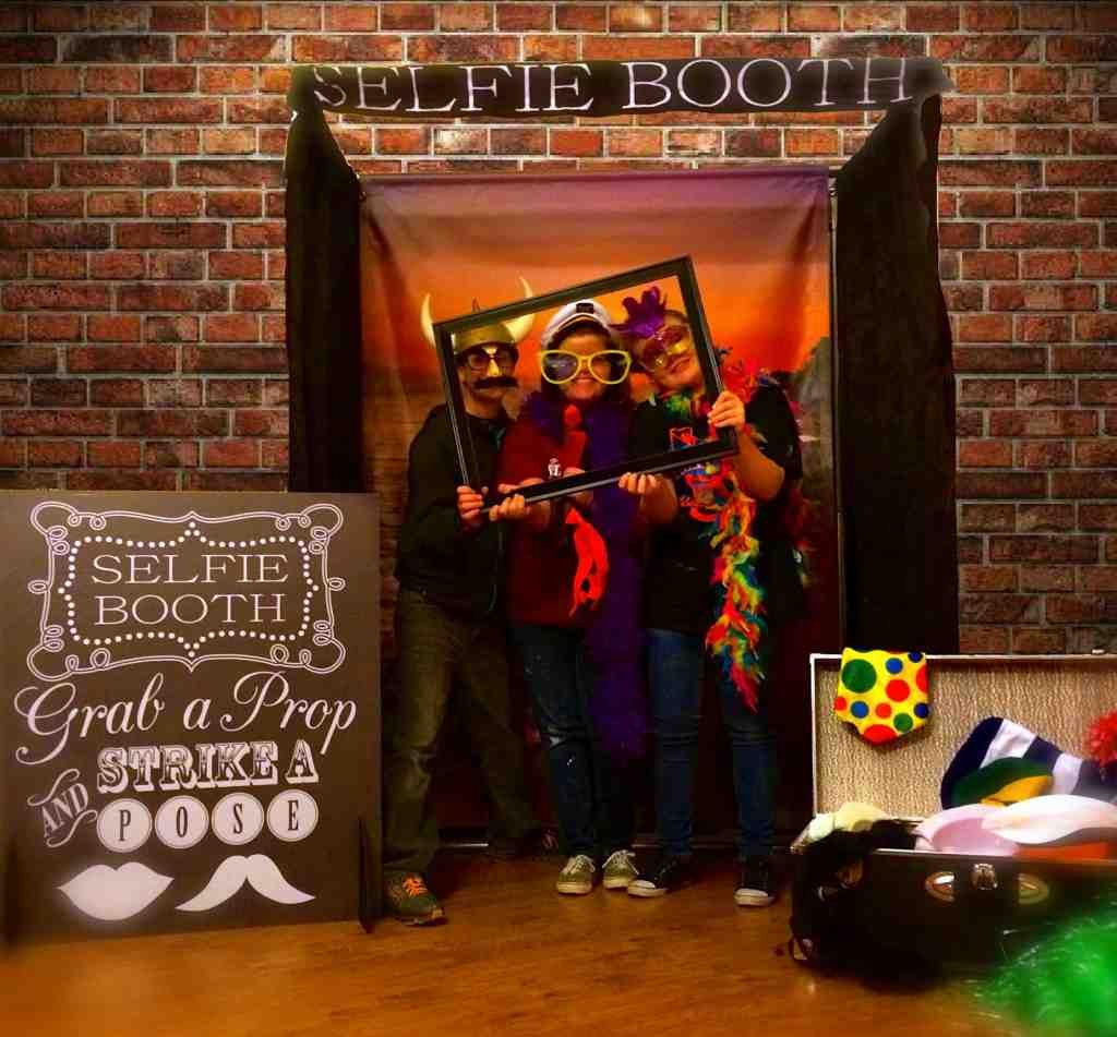 Guests enjoying a fun selfie booth with props at an event