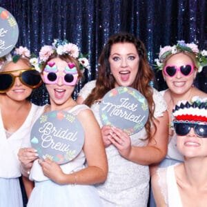 Bride and bridal party enjoying a wedding photo booth with fun props and signs