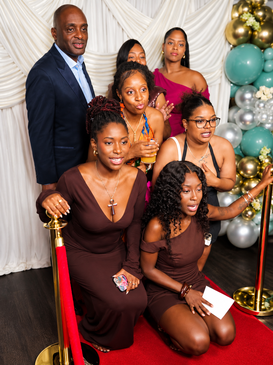 Wedding guests in evening wear posing together on the red carpet with VIP stanchions at a photo booth hire event